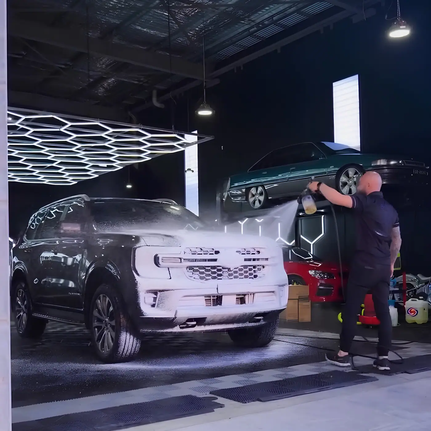 SUV covered in snow foam during the decontamination stage of a full detail
