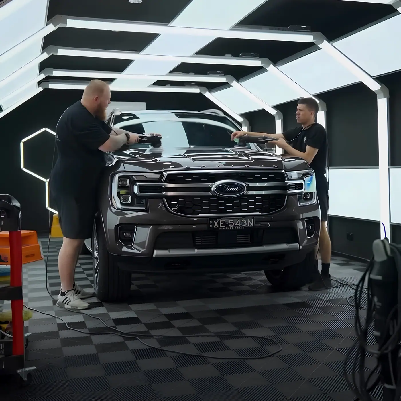 Machine polishing a bonnet under correction lighting during paint correction